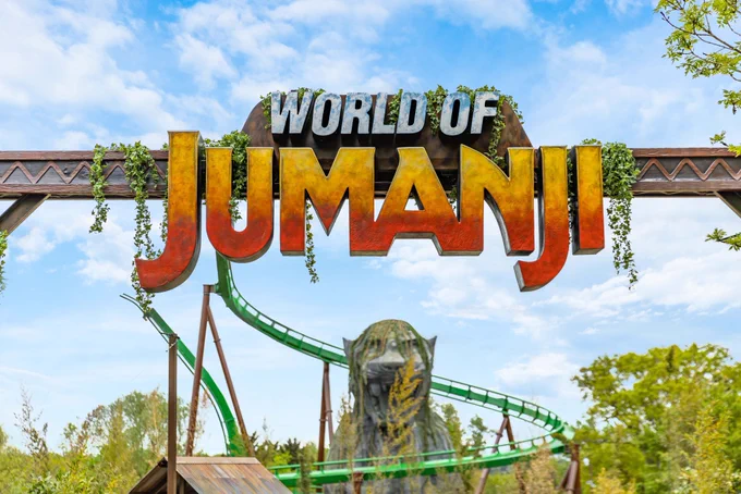 World of Jumanji entrance portal with large sign overhead that reads ‘World of Jumanji’. In the background is new rollercoaster track, Mandrill Mayhem, with the 55ft jaguar shrine underneath a blue sky with clouds.