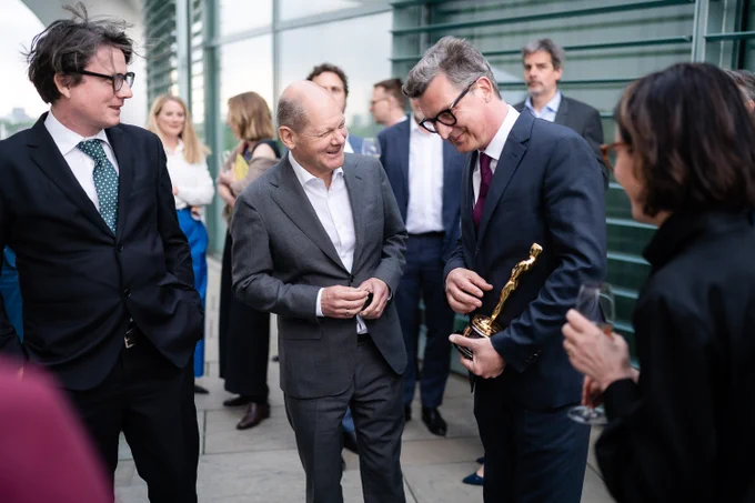 Der Bundeskanzler lässt sich eine der Oscar-Trophäen zeigen.