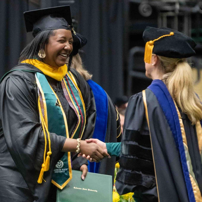 A graduate shakes hands with President Amy Parsons.