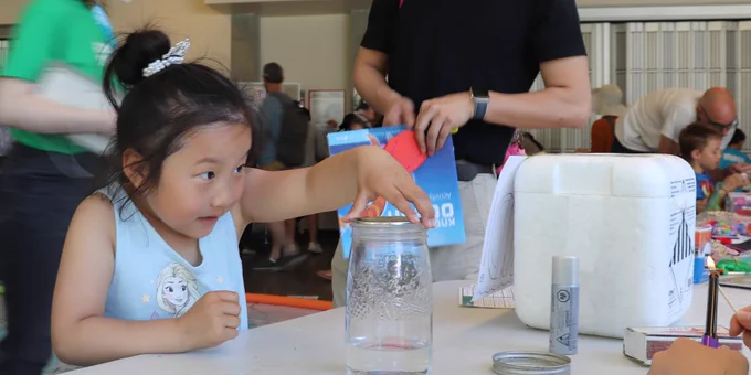 Young girl holding the lid on a jar while making a cloud. 