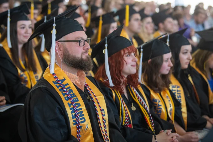 A group of graduates sits during a Kent State commencement ceremony. 