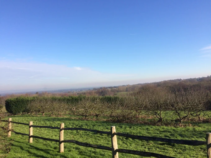 Job vacancy at rural location in electronic engineering company. Image shows blue sky, green grass foreground, orchards and far reaching views of Kent in the South East of England.