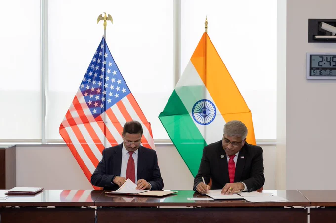 Secretary Alkesh Kumar Sharma and Director Panchanathan sign the NSF-India implementation arrangement for research agency partnership in front of the American and Indian flags.