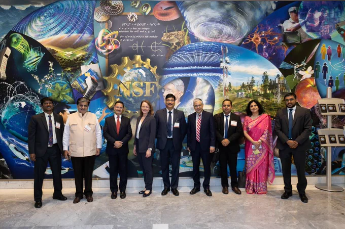 A group of NSF and Indian delegates stand in front of a vibrant mural at NSF headquarters.