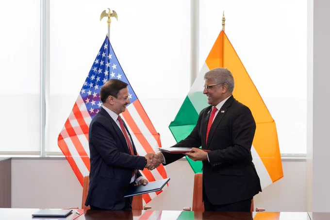 Ministry of Electronics and Information Technology Secretary Alkesh Kumar Sharma and NSF Director Sethuraman Panchanathan shake hands in front of the American and Indian flag after the implementation arrangement signing.