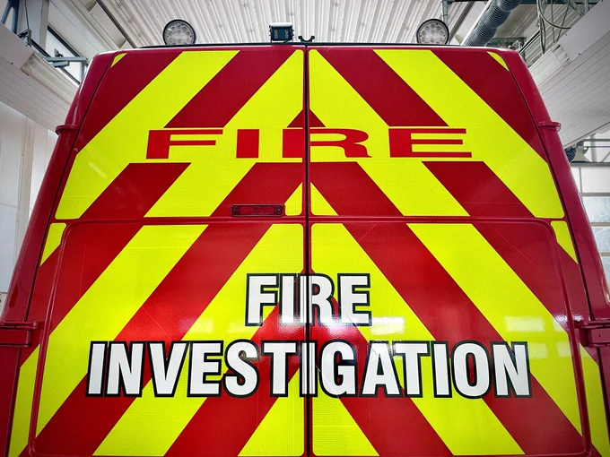 photograph of the back doors of a van. the van is painted Battenberg red and yellow, and reads 'fire investigation'