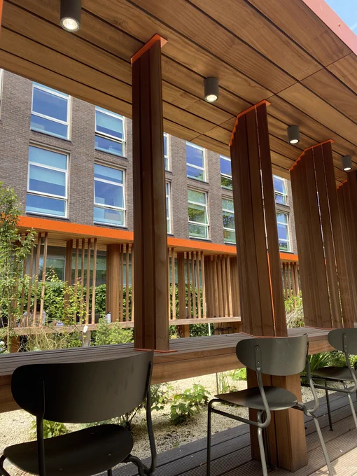 Close up image of wooden seating frames and chairs overlooking the greenery of the garden