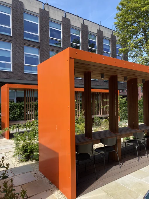 View of library garden shows greenery & blue skies contrasted with orange seating frames