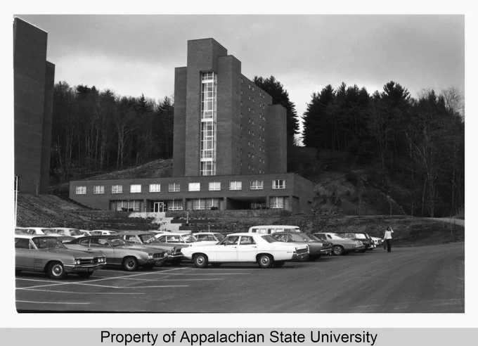 This image shows the northeastern side of Winkler Residence Hall, built 1974. The eastern (front) entrance can be seen at the base of the building, and the adjacent parking lot is in the foreground. A figure can be seen walking away from the building. Winkler is part of the Stadium Heights Community of residence halls, and is located between Eggers and Frank Residence Halls. (https://omeka.library.appstate.edu/items/show/7425)