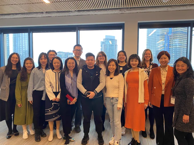 A delegation of philanthropists from China stand to take a group photo. 