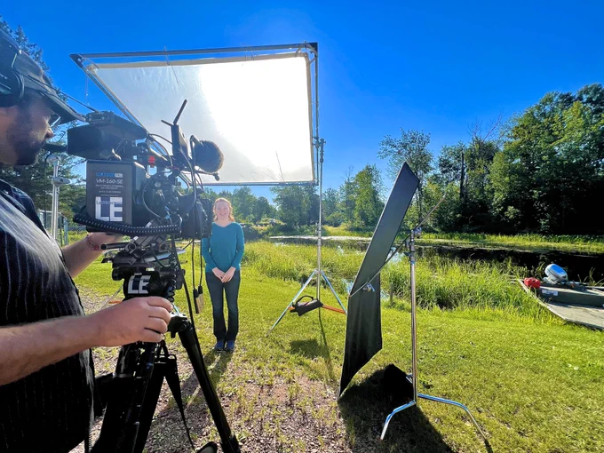 Naomi Tillison of the Mashkiiziibii Natural Resources Department stands among film equipment next to an access point to the Bad River.