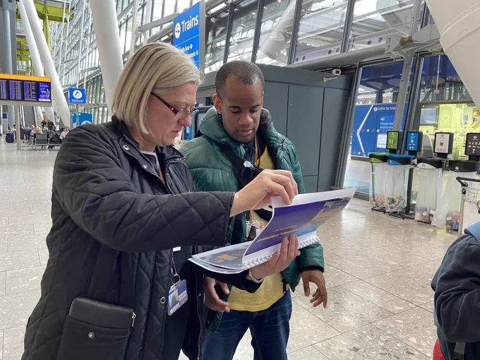 A volunteer supporting a HEX student to navigate the station using a booklet produced by HEX for the event