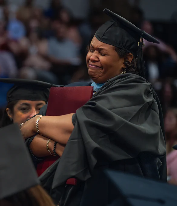 Kimberly Manning hugs her diploma at the Graduate Program Commencement.