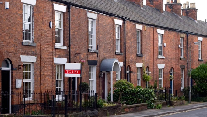 Image of rows of red brick houses with one rent sign