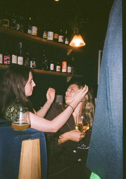 The same woman is having her make up touched up by her lovely friend.
