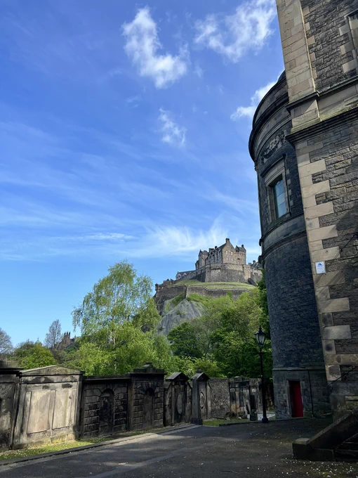 Picture from a church yard, looking up towards the direction of Edinburgh castle on a sunny day with blue sky and only a few clouds.