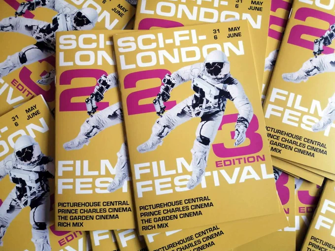 Photo of a pile of printed Sci-Fi London festival programmes with a bright yellow cover with a floating astronaut 