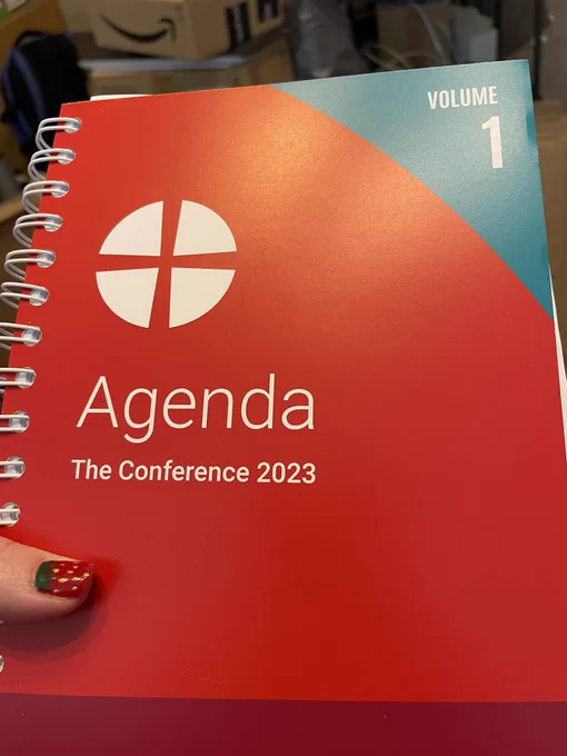 A picture of a red bound book that says “Agenda. The conference 2023” under the methodist logo in white