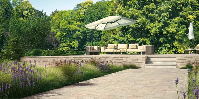 Garden courtyard with porcelain pavers and natural stone along with a seating area and blooming lavender for article introducing concept of solar reflectance index (SRI) for building materials including decking and siding products.