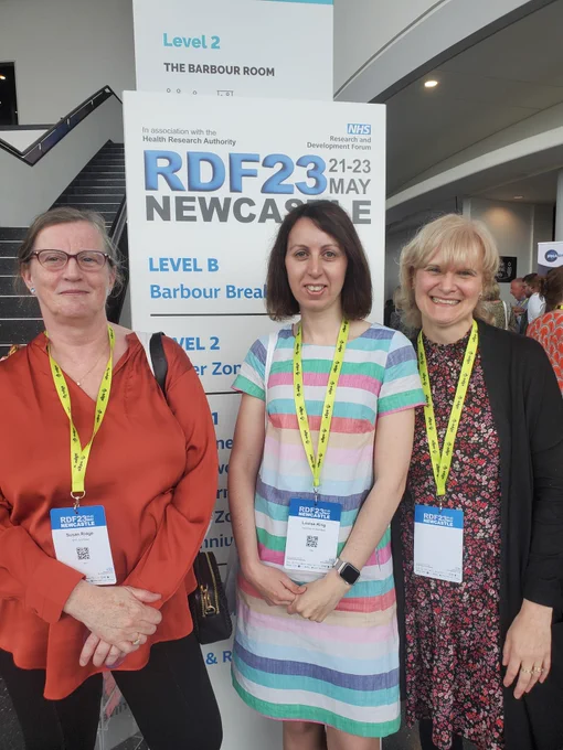 3 ladies smiling, standing in front of RDF Newcastle banner
