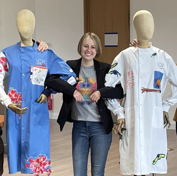 Laura Nuttall smiling while locking arms with two mannequins wearing ICR lab coats re-designed by artist Rosalind Wyatt.