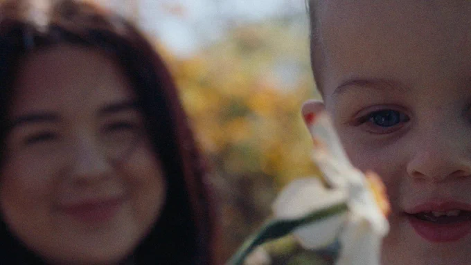 A child with her mother playing with a daffodil. 