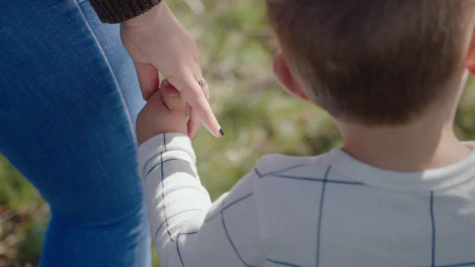 A child holding the hand of his mother.