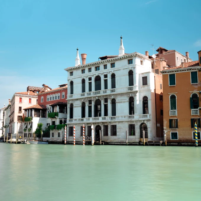 An impressive white building (The Palazzo Giustinian Lolin) overlooking the Grand Canal in Venice on a bright sunny day. 