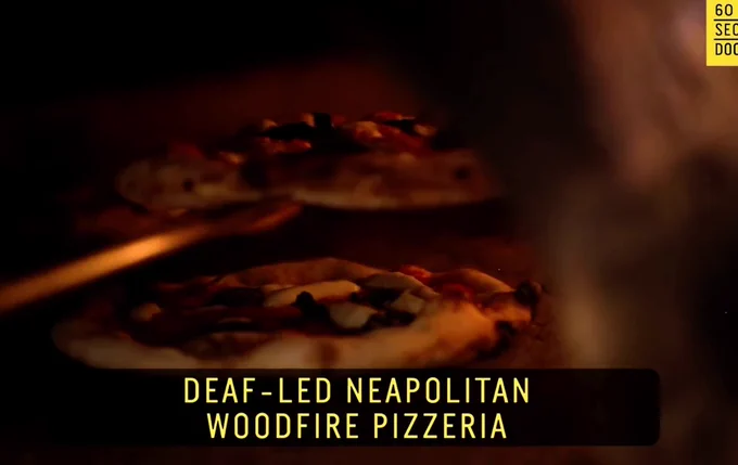 Mozzeria image of wood fired pizza in an oven CC text reads: Deaf-led neapolitan woodfire pizzeria