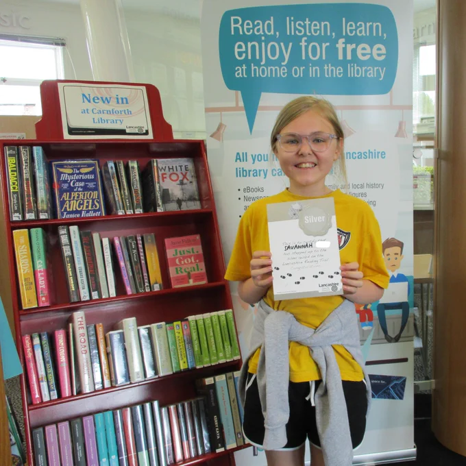 A child holding a Reading Trail certificate.