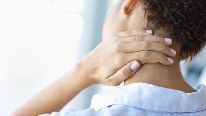 A stressed person rubs the back of their neck.