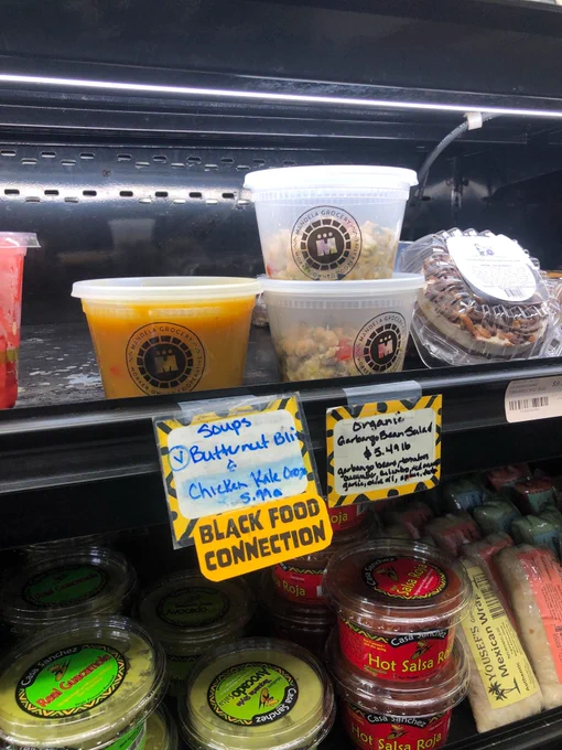 a photo of a grocery fridge shelf with transparent containers of soup and salad with a label that reads “black food connection” 