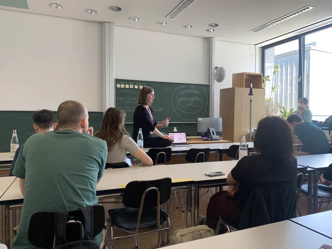 A speaker presenting in a classroom on her laptop