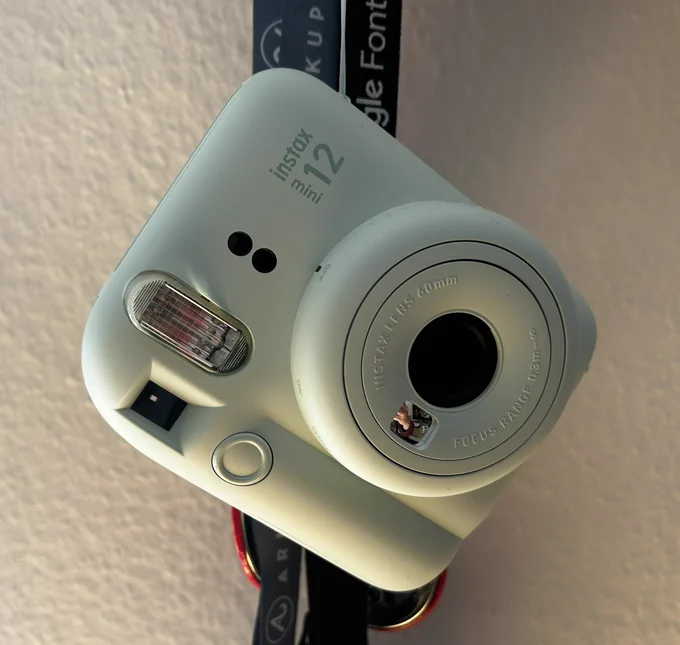 Picture of a instant camera hanging before a white wall