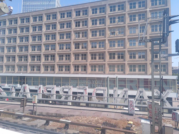 Foto: Bürogebäude des DFN-Vereins, vom S-Bahnsteig aus fotografiert. Am unteren Bildrand ist die Bahnhofsbeschriftung "Alexanderplatz" von hinten zu erkennen.