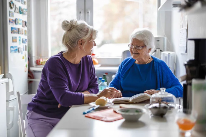 An elderly women being looked after by her carer at home.  