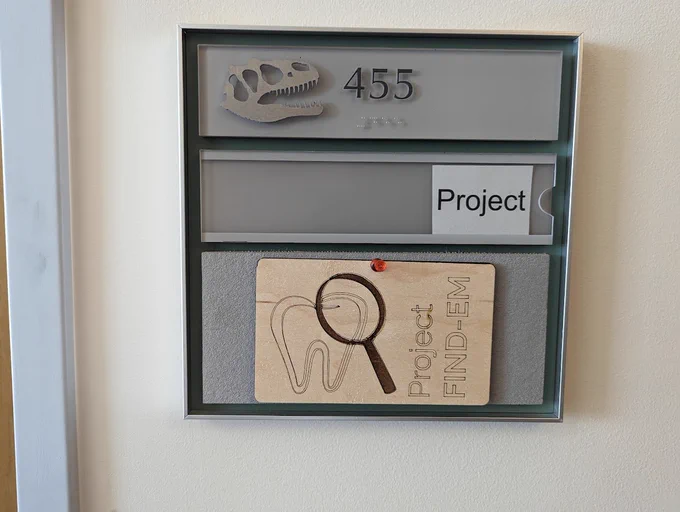 Photo of office room number with laser engraved wood plaque of the FIND-EM logo below it