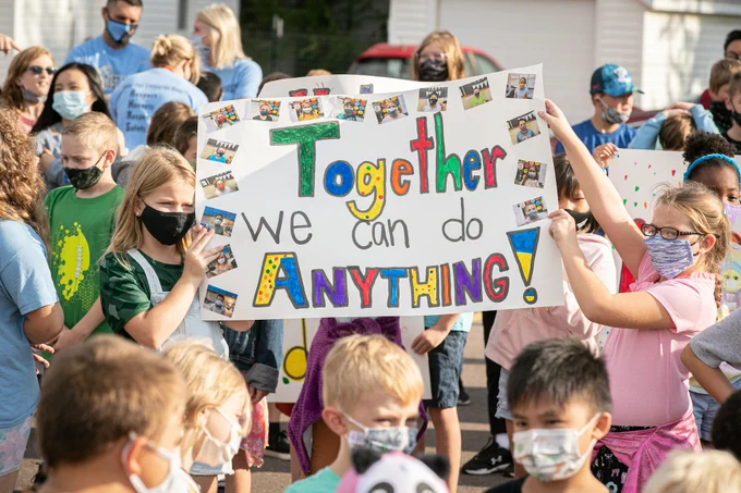 Photo of young students holding a sign that reads "Together We Can Do Anything!"
