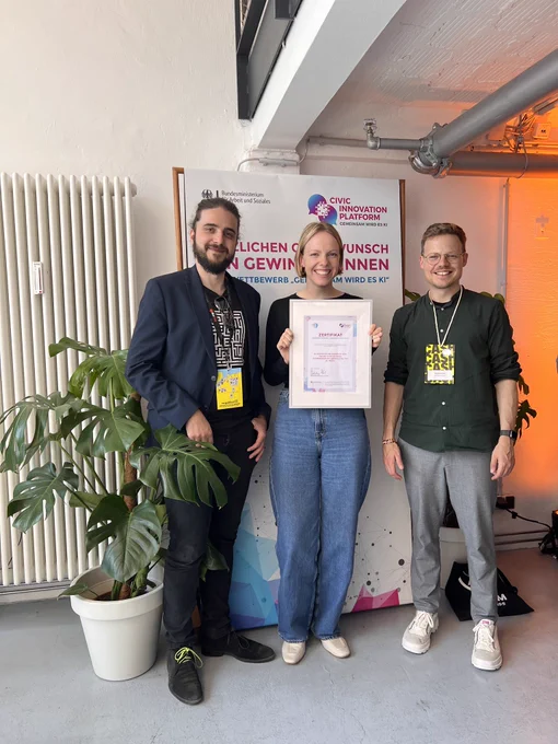 Das Bild zeigt Tobias, Anke und Moritz vor einem Aufsteller der Civic Innovation Platform.