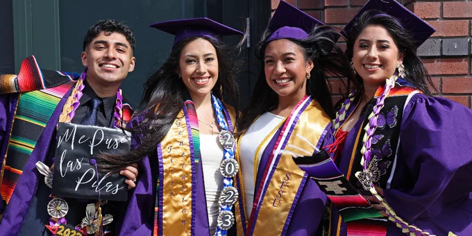 Four graduates at SF State Commencement pose for a photo together
