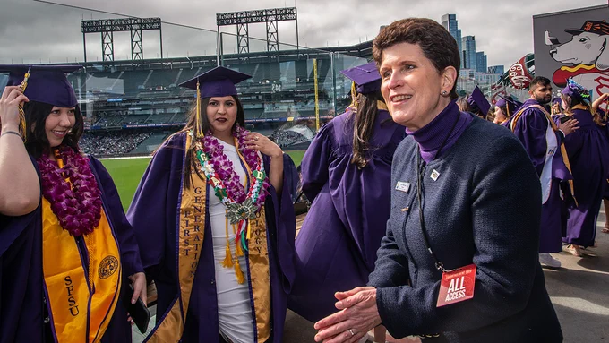 SF State President Lynn Mahoney applauds graduates while walking through the Grad Zone at Commencement before the ceremony