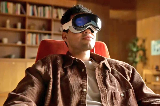 person seated using new Apple Vision Pro headset watching cinema size screen at home in Augmented Reality
