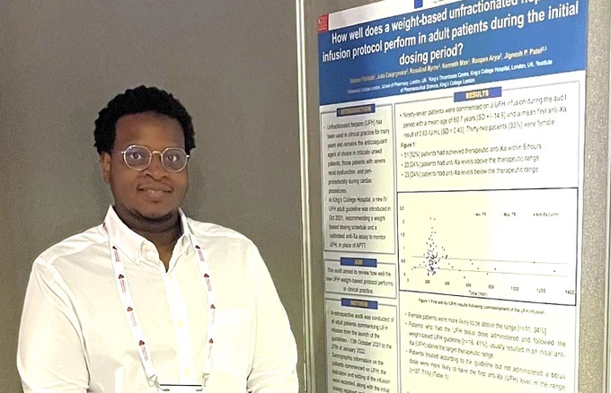 Osama Fallatah standing next a a research poster about medicine doses.