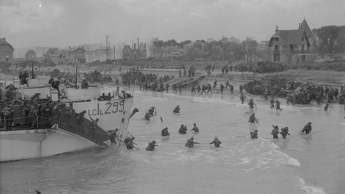 Canadian troops disembarking from landing craft and making their way to the shore.
