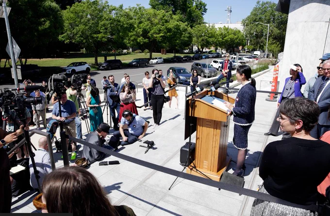 Reporters gather around to listen to Sandy Chung, ED of the ACLU 