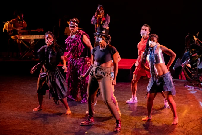 five people are dancing wearing masks.