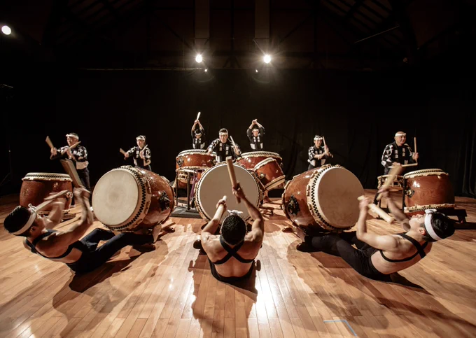 People gather in a circle to play drums.