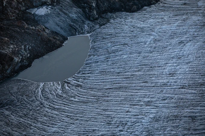 A photograph of the bottom of a mountain surrounding a small lake
