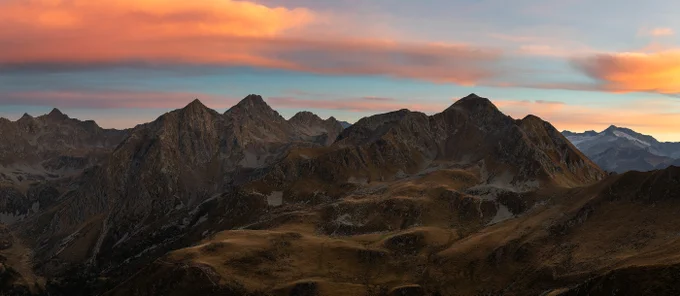 A photograph of mountains in the not-so-far distance with pink and orange clouds rolling in.