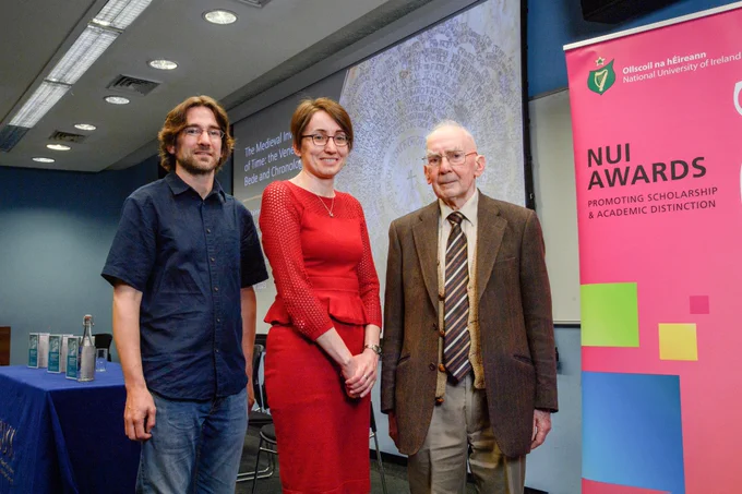 Dr Pádraig MacCarron, Dr Máirín MacCarron and Patrick MacCarron in the room where the lecture and reception took place. Beside them is an NUI Awards banner.